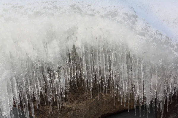Icicles on a stone on a freezing river — Stock Photo, Image