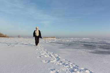 Dondurulmuş bir buz üzerinde çalışan bir bej kazaklı olgun adam