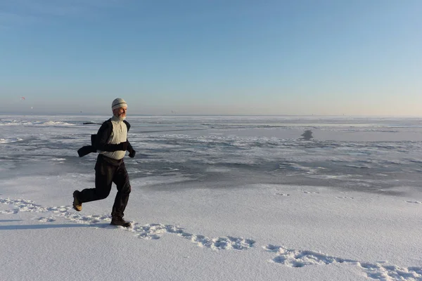 Dojrzały mężczyzna w beżowy sweter biegnącą przez lód mrożone — Zdjęcie stockowe