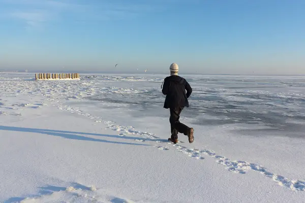 Пожилой человек в бежевом свитере, бегущий по льду замерзшего — стоковое фото