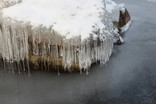 Ijspegels op een steen op een ijskoude rivier — Stockfoto