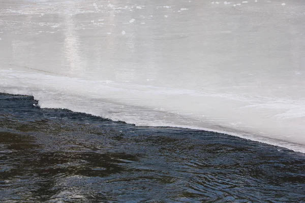 Eau qui coule à travers la surface de glace fondante de la rivière — Photo