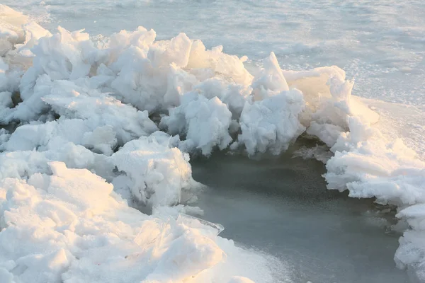 Praskliny s ledovými krystaly na zamrzlou řeku při západu slunce — Stock fotografie