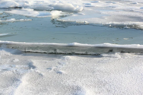 Rachaduras com cristais de gelo no rio congelado ao pôr-do-sol — Fotografia de Stock