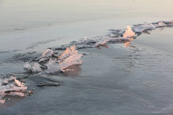 Fissures avec cristaux de glace sur la rivière gelée au coucher du soleil — Photo