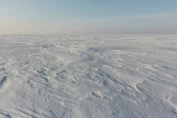 Opluchting besneeuwde oppervlak van de bevroren rivier bij dageraad — Stockfoto