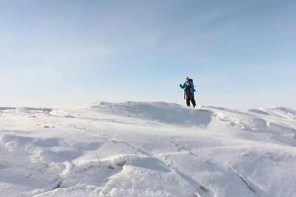 Mann in blauer Jacke mit Rucksack fährt Ski auf dem Eis — Stockfoto