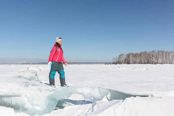Счастливая женщина в красной куртке, стоящая на льдине на замерзшей реке — стоковое фото