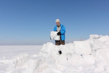Kışın bir Eskimo bir glade üzerinde bina bir mavi ceketli adamı