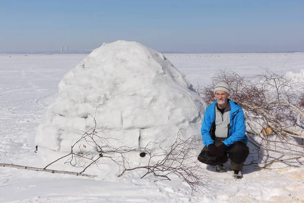 Hombre sentado junto a un iglú en un claro en el invierno —  Fotos de Stock
