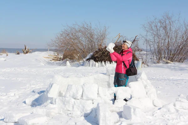Glückliche Frau in roter Jacke baut ein Iglu auf einer Schneelandschaft — Stockfoto