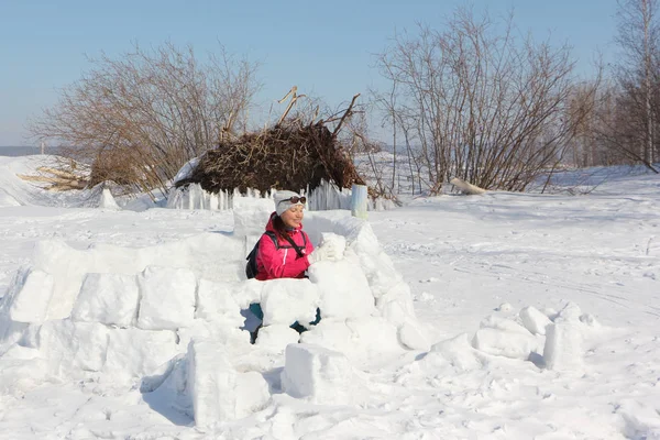 Mujer feliz una chaqueta roja construyendo un iglú en un claro de nieve — Foto de Stock