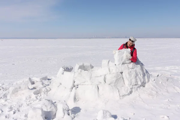 Mujer feliz una chaqueta roja construyendo un iglú en un claro de nieve — Foto de Stock