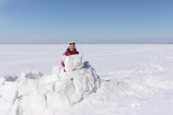 Mujer feliz una chaqueta roja construyendo un iglú en un claro de nieve —  Fotos de Stock