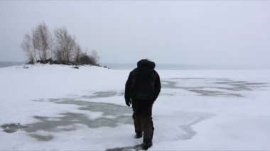 Adam bir erime nehir yüzey, Ob depo, Rusya üzerinde bir kar fırtınasında yürüyüş bir sırt çantası ile 