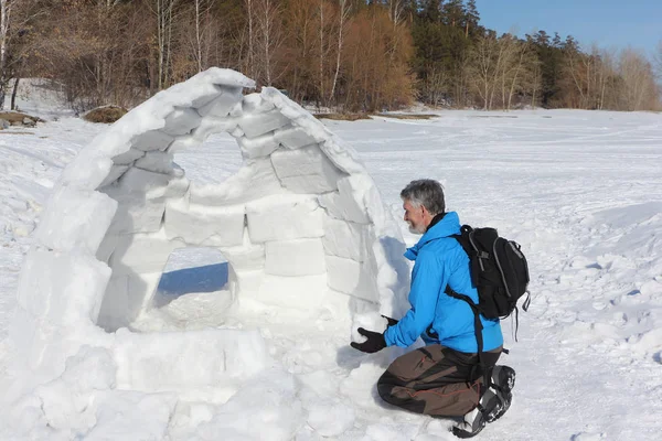 Hombre con chaqueta azul construyendo un iglú en un claro —  Fotos de Stock