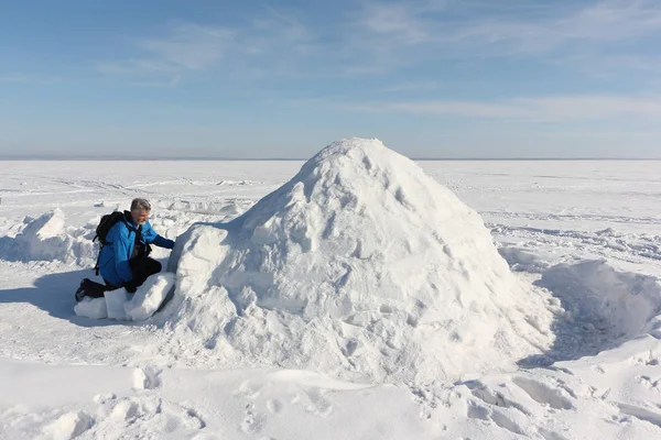 Hombre sentado a la entrada de un iglú en un embalse nevado en invierno — Foto de Stock