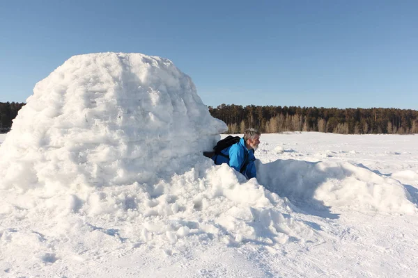 Człowiek siedzi w igloo na zamarzniętym zbiorniku w zimie — Zdjęcie stockowe