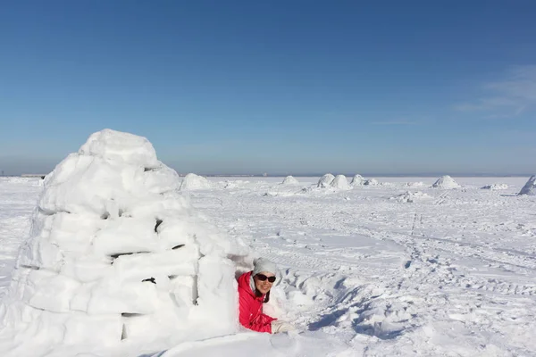 穿着红色夹克的快乐女人躺在雪地上的空地上的冰屋里 — 图库照片