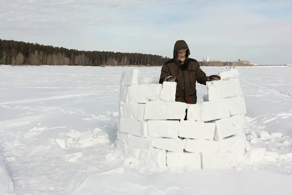 Man building an igloo from snow blocks in the winter — Stock Photo, Image