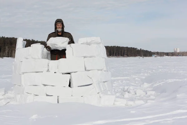 Mann baut im Winter ein Iglu aus Schneeblöcken — Stockfoto