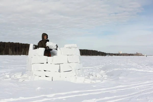 Man building an igloo from snow blocks in the winter — Stock Photo, Image