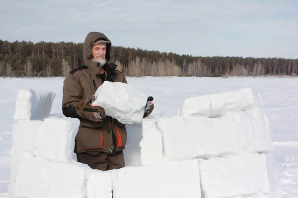 Mann baut im Winter ein Iglu aus Schneeblöcken — Stockfoto