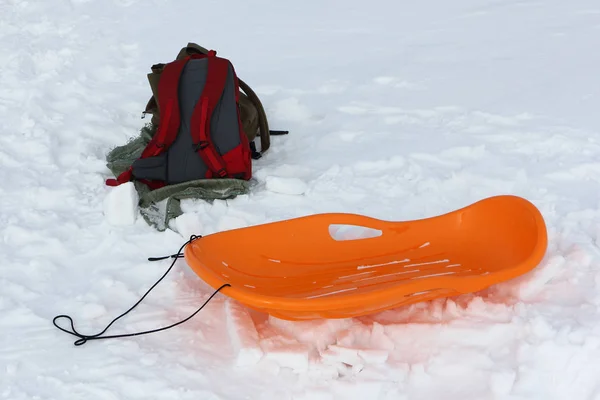 Mochila y trineo de plástico en la nieve — Foto de Stock