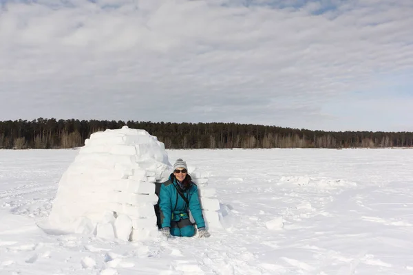 따뜻 한 옷을 입은 행복 한 여인 이 겨울에 수수께끼 옆에 앉아 있는 모습 — 스톡 사진