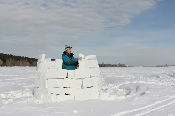 Mujer feliz en ropa de abrigo construyendo un iglú en un claro de nieve — Foto de Stock