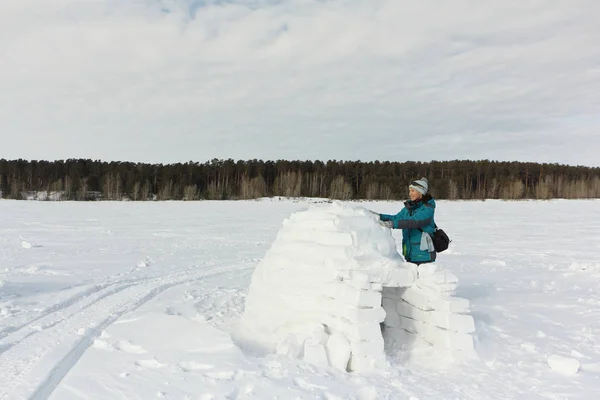 Mujer feliz en ropa de abrigo construyendo un iglú en un claro de nieve —  Fotos de Stock