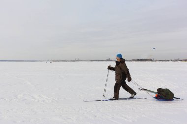 Adam kışın donmuş bir nehirde kızakla kayak yapıyor.