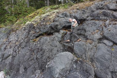 Sırt çantalı bir adam kayadan aşağı iniyor.