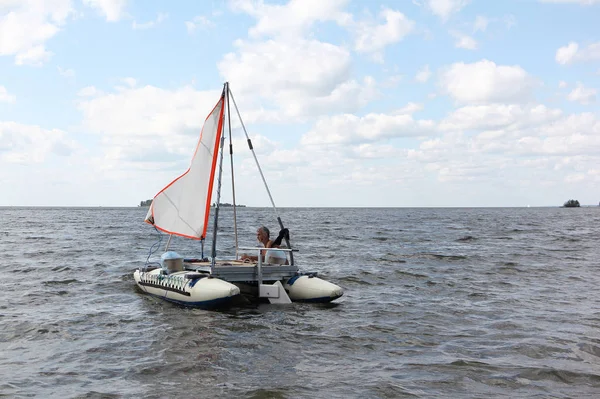 Man lowering catamaran into river, Novosibirsk, Russia