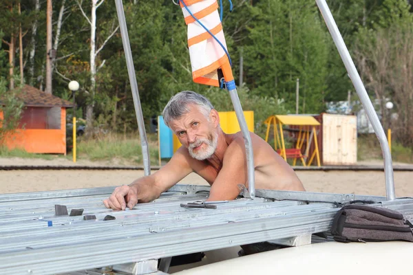 Uomo che raccoglie un catamarano sulla riva del fiume, Novosibirsk, Russia — Foto Stock