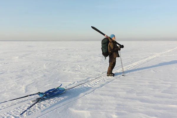 Homem com esquis e trenó na superfície nevada do rio — Fotografia de Stock