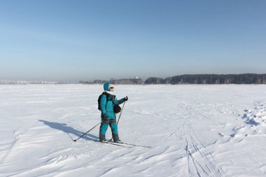 Happy woman with a  backpack  skiing on a frozen river