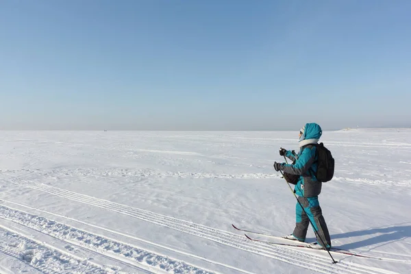 Gelukkige vrouw met een rugzak skiën op een bevroren rivier — Stockfoto