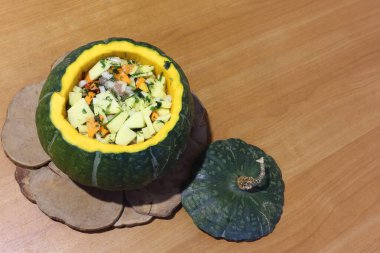 Sebzelerle doldurulmuş çiğ yeşil balkabağı masanın üzerinde duruyor.