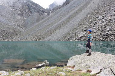 Dağ Ruhları Gölü 'nün kıyısında, Altai dağlarında, Rusya' da bir taşın üzerinde duran mutlu kadın.