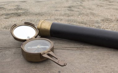 Vintage bronze compass and spyglass on the background of the sea