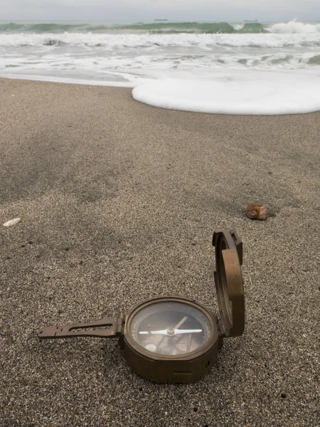 Bronzen kompas op het strand op zee achtergrond — Stockfoto