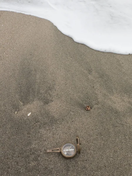 Schöner alter Kompass auf dem Sand neben den Wellen — Stockfoto