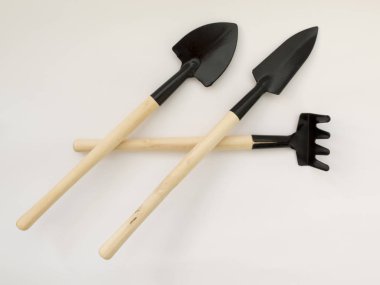 Demir kürek ve beyaz zemin üzerine ahşap direklerin tırmıkla