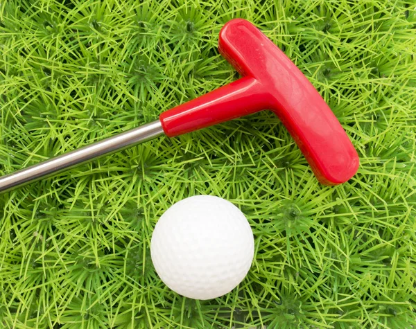 Póquer vermelho e bola de golfe em um fundo de grama verde — Fotografia de Stock