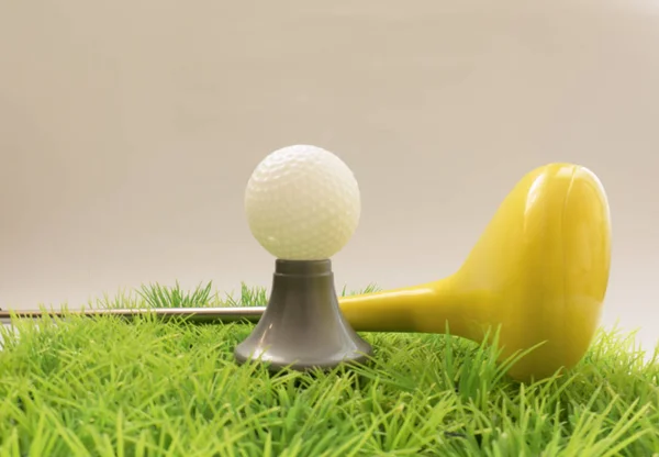Brinquedo amarelo putter e bola de golfe na grama — Fotografia de Stock