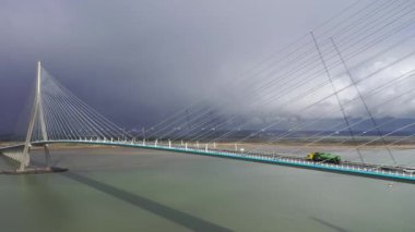 Fransa, Avrupa 'daki bir asma köprüde uçan araba ve kamyon trafiğinin hava görüntüsü. Pont de Normandy, Fransa 'nın kuzeyindeki büyük asma köprü Seine Nehri' ni gökkuşağı, Normandiya, Fransa 'da bulutlu bir gökkuşağı ile geçen köprü..