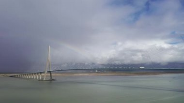 Köprüden geçen kamyonlar. Pont de Normandy, Fransa 'nın kuzeyindeki büyük asma köprü Seine Nehri' ni gökkuşağı, Normandiya, Fransa 'da bulutlu bir gökkuşağı ile geçen köprü..