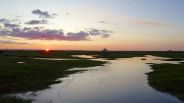  Le Mont-Saint-Michel - Fransa 'da gün batımında Le Mont-Saint-Michel' in önündeki tuz bataklıklarının üzerinden uçmak