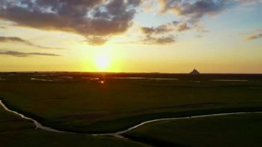 Le Mont-Saint-Michel - Fransa 'da gün batımında Le Mont-Saint-Michel' in önündeki tuz bataklıklarının üzerinden uçmak